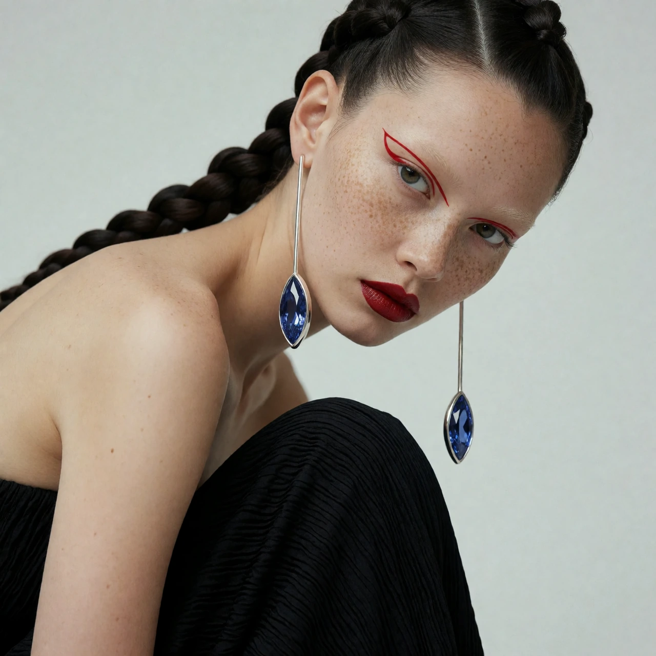 Avant-garde luxury jewelry campaign inspired by contemporary fashion editorials. A model with distinctive editorial beauty, freckles, pale skin, bleached eyebrows and sculptural braided hair. Strong asymmetrical pose with the body folded diagonally w