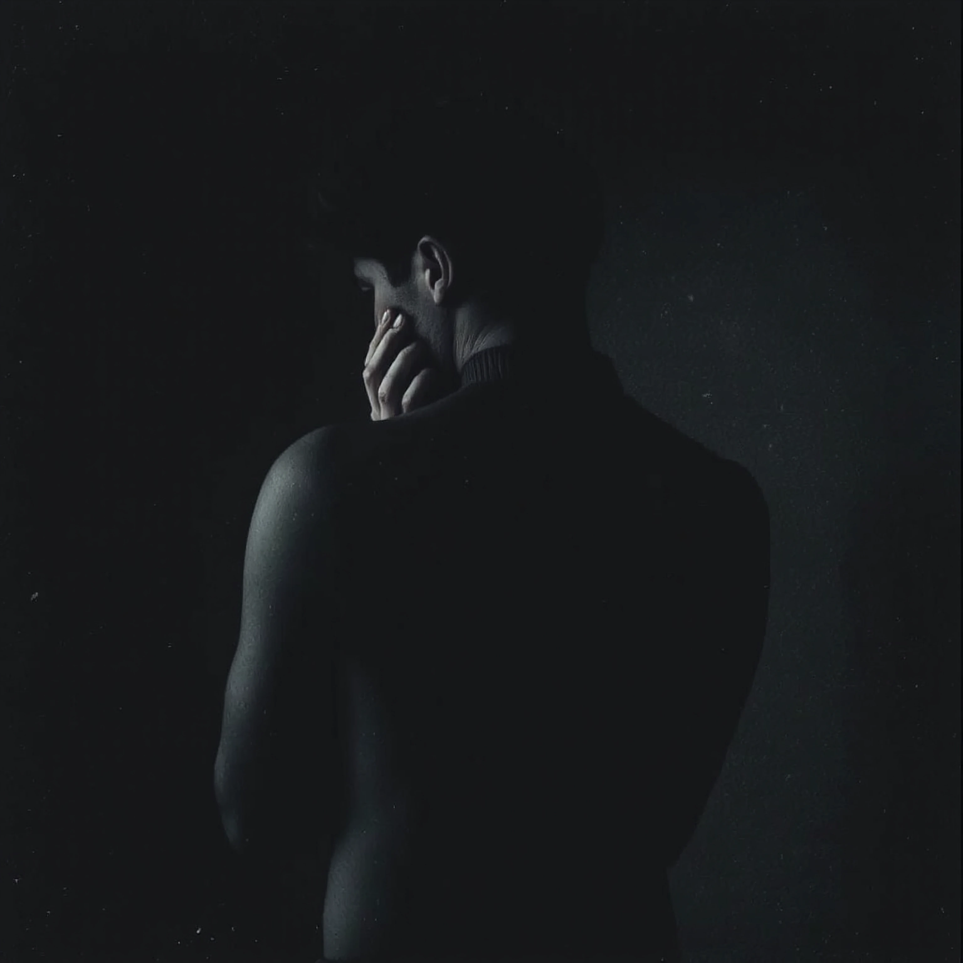 a solitary figure caught in the fragile moment between composure and breaking, shoulders curved inward protectively, hands trembling or pressed agains