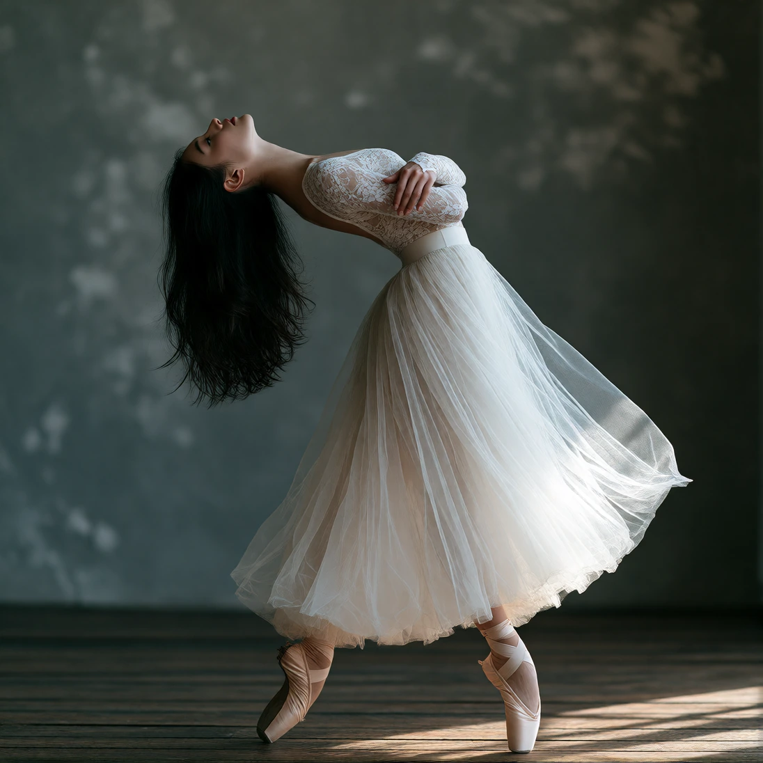 Female ballet dancer en pointe, dark wooden floor, leaning torso dramatically backward, long straight black hair hanging down, white lace long-sleeved top, flowing white tulle skirt held against chest, pale pink pointe shoes, mottled gray textured st