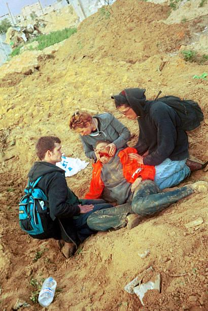 american peace activist Rachel Corrie, lies bleeding while being helped by colleagues after she was…