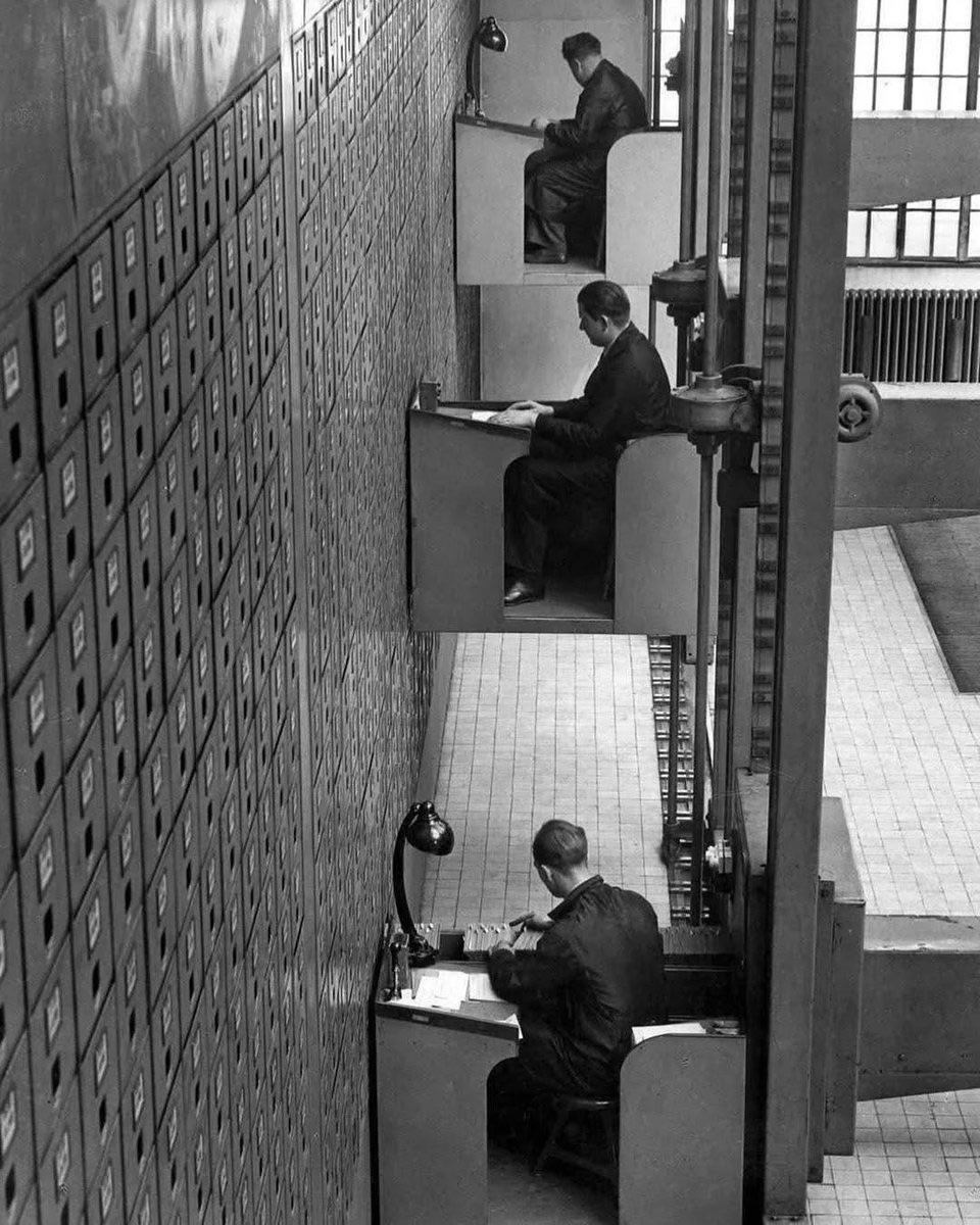 file clerks working at their electric elevator desks in Prag…