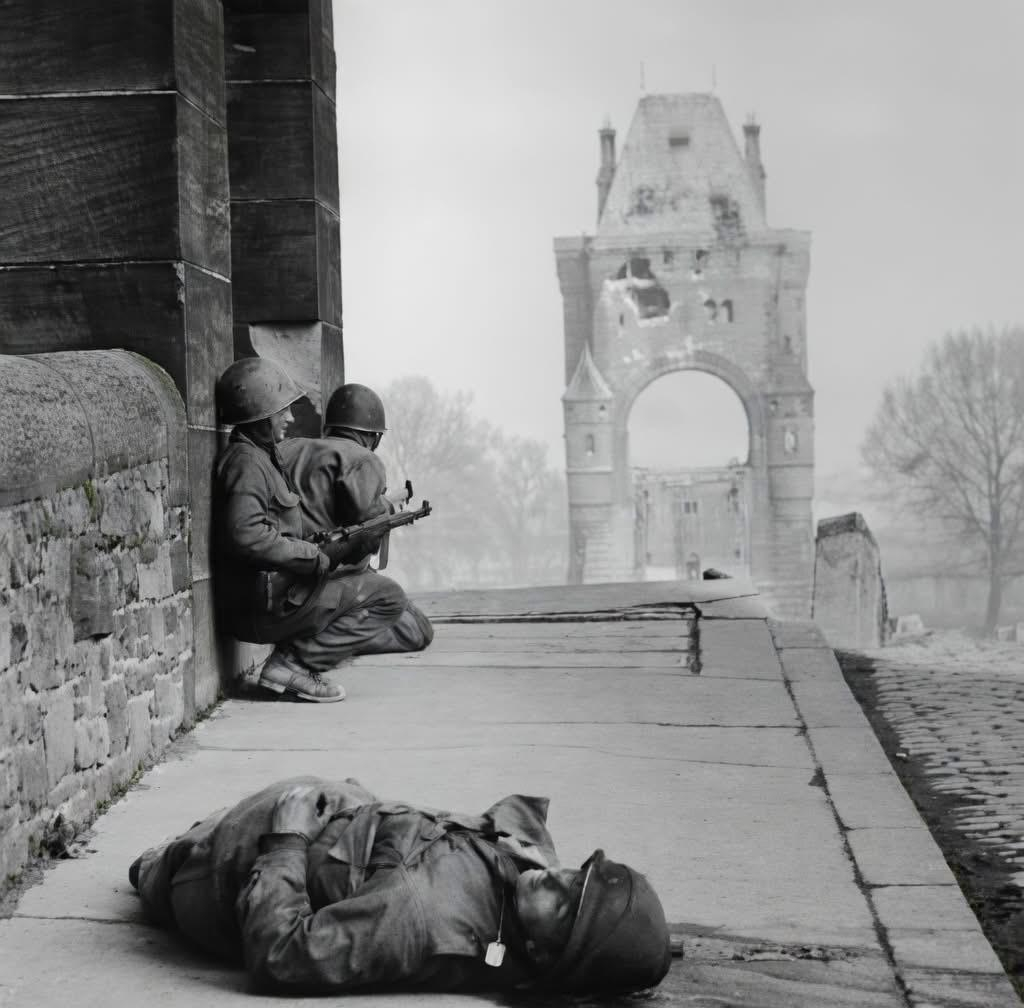 a dead GI and US troops under sniper fire on the Nibelungen Bridge in Worms, Germany. 28 March 1945