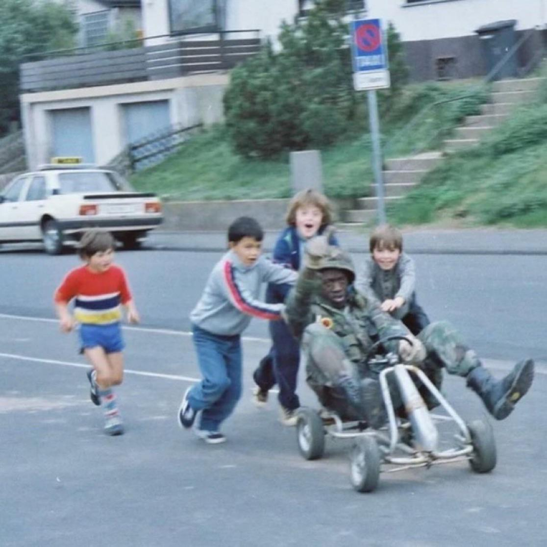 u.S. soldier playing with local german kids on a cart in west germany, (1980s)