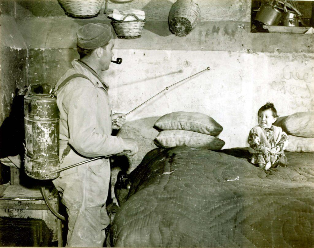 soldier in an Italian home spraying a mixture of DDT and kerosene to control malaria, 1945