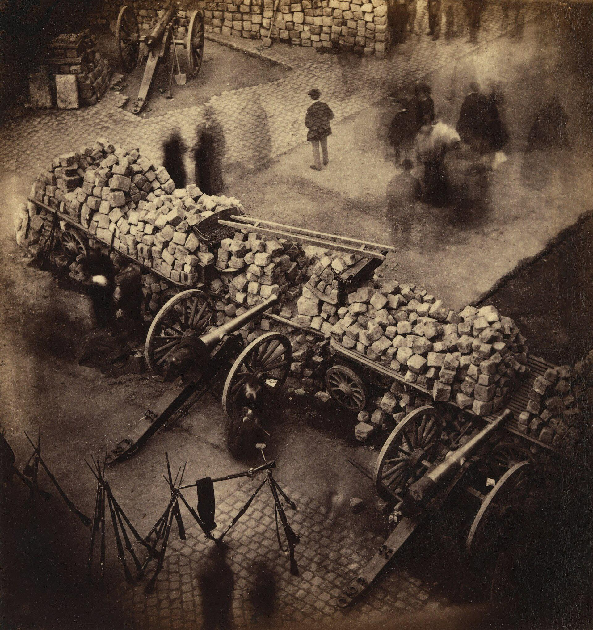 photograph of a barricade during the Paris Commune, April 1871; the blurred figures are a result of…