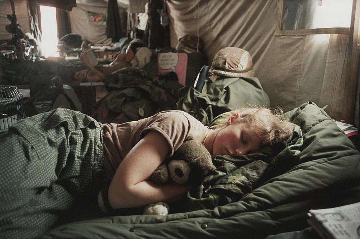 exhaust U.S. Army nurse Amy Stuart, 5th MASH unit in Saudí Arabia naps on a cot while hugging a tedd…